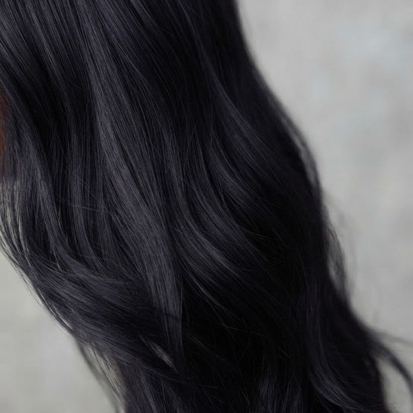 Gros plan sur la texture et les mèches de cheveux noirs de la perruque Naomi BYNERIMA.